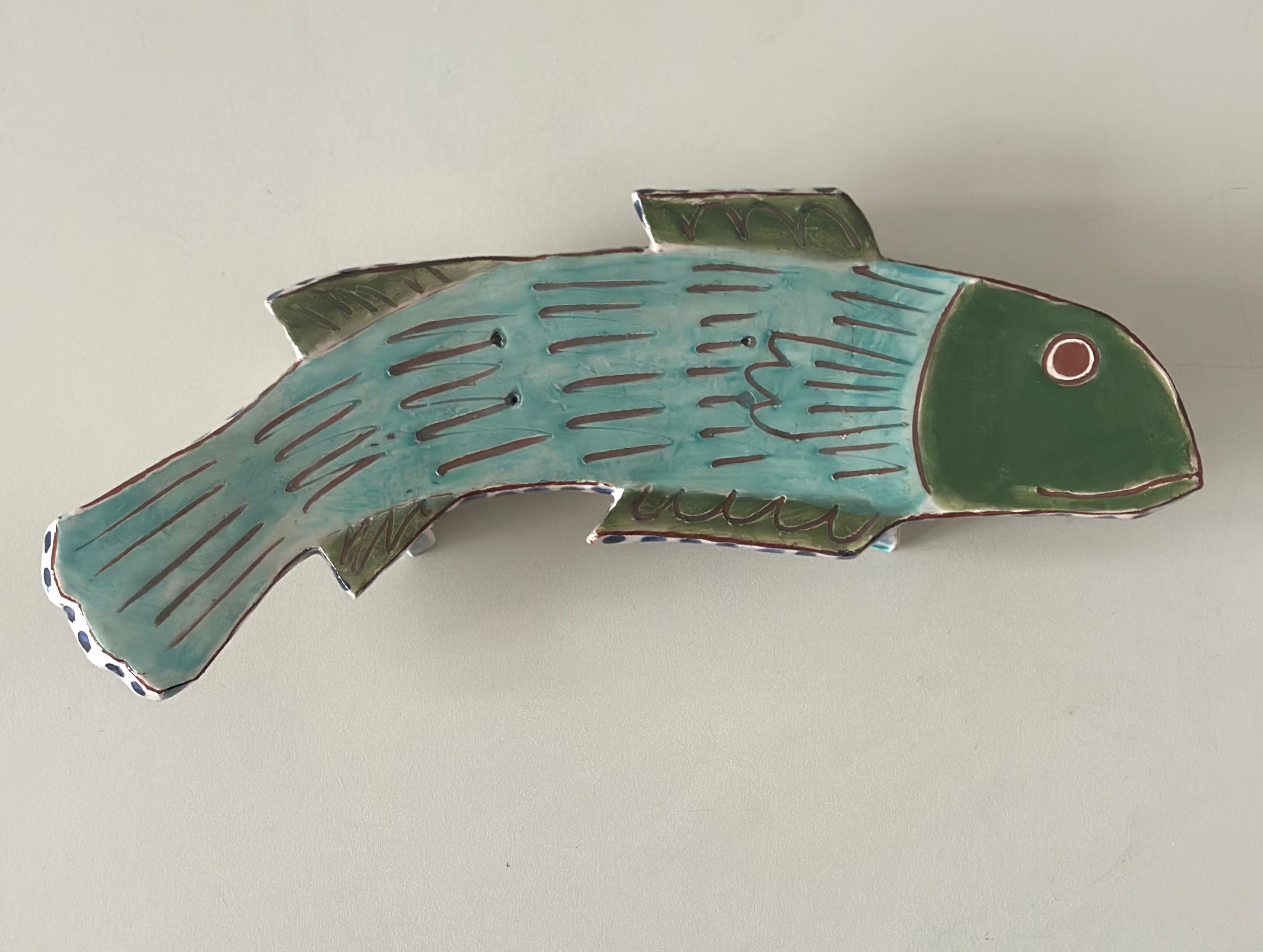 Ceramic fish-shaped object on a plain background