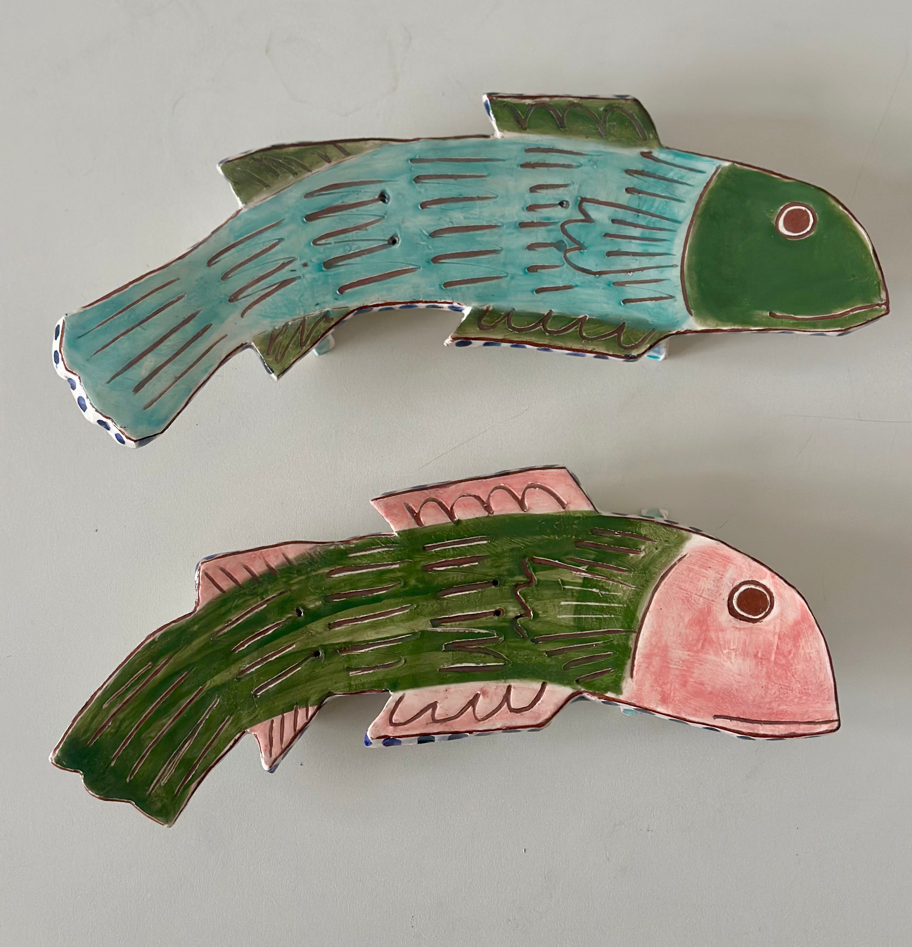 Two ceramic fish figurines on a light gray background