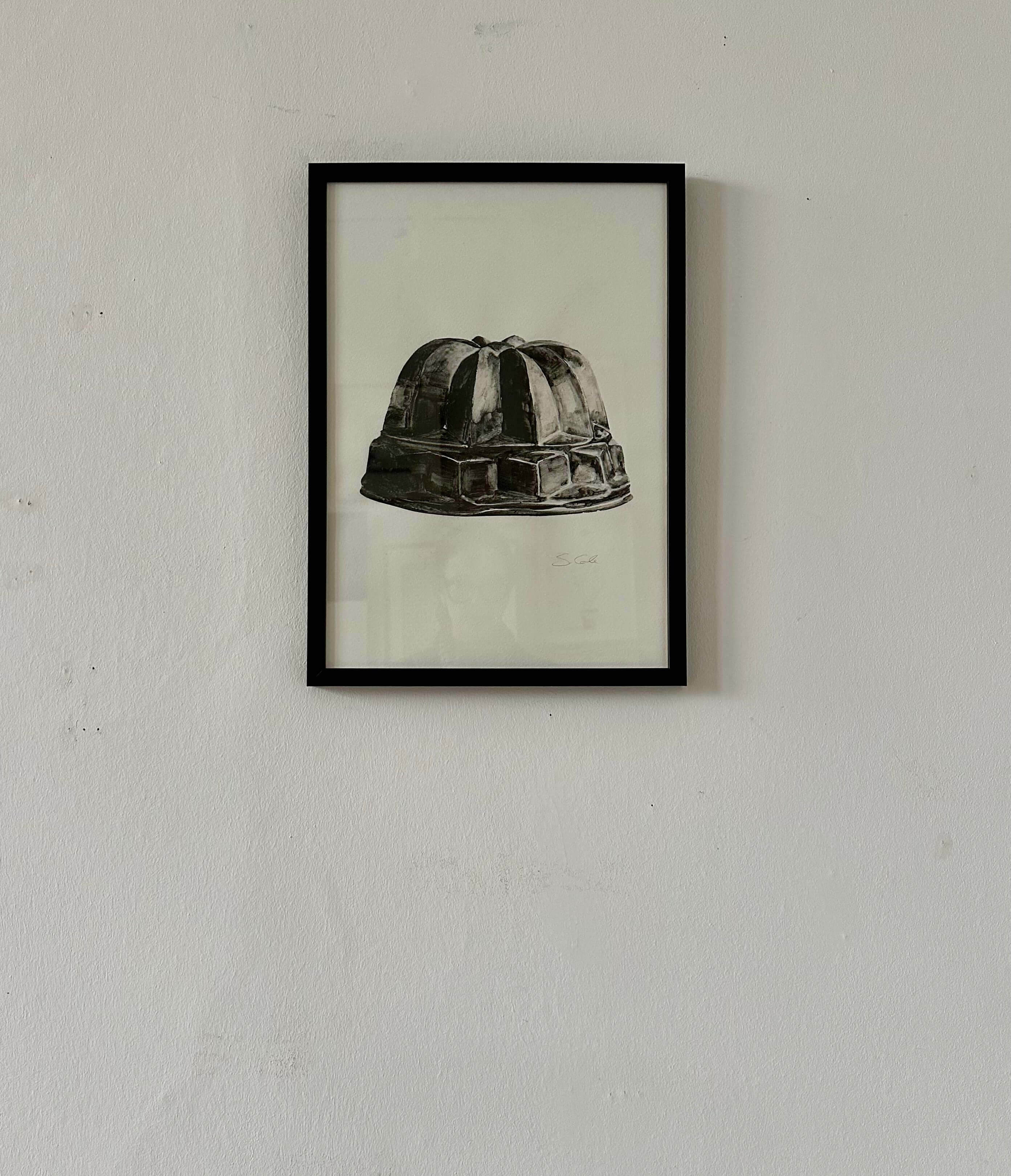 Jelly Mold II by Sophie Cole. Framed black and white print of a jelly mould on a plain wall.