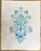 Little Garden 'Blue' by Neera Sehgal depicting white fabric with blue floral and leaf pattern on a wooden surface
