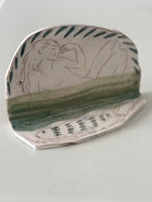 Ceramic dish with artistic depiction of a woman and green patterns on a white background