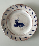 Ceramic plate with blue goat design on a white background