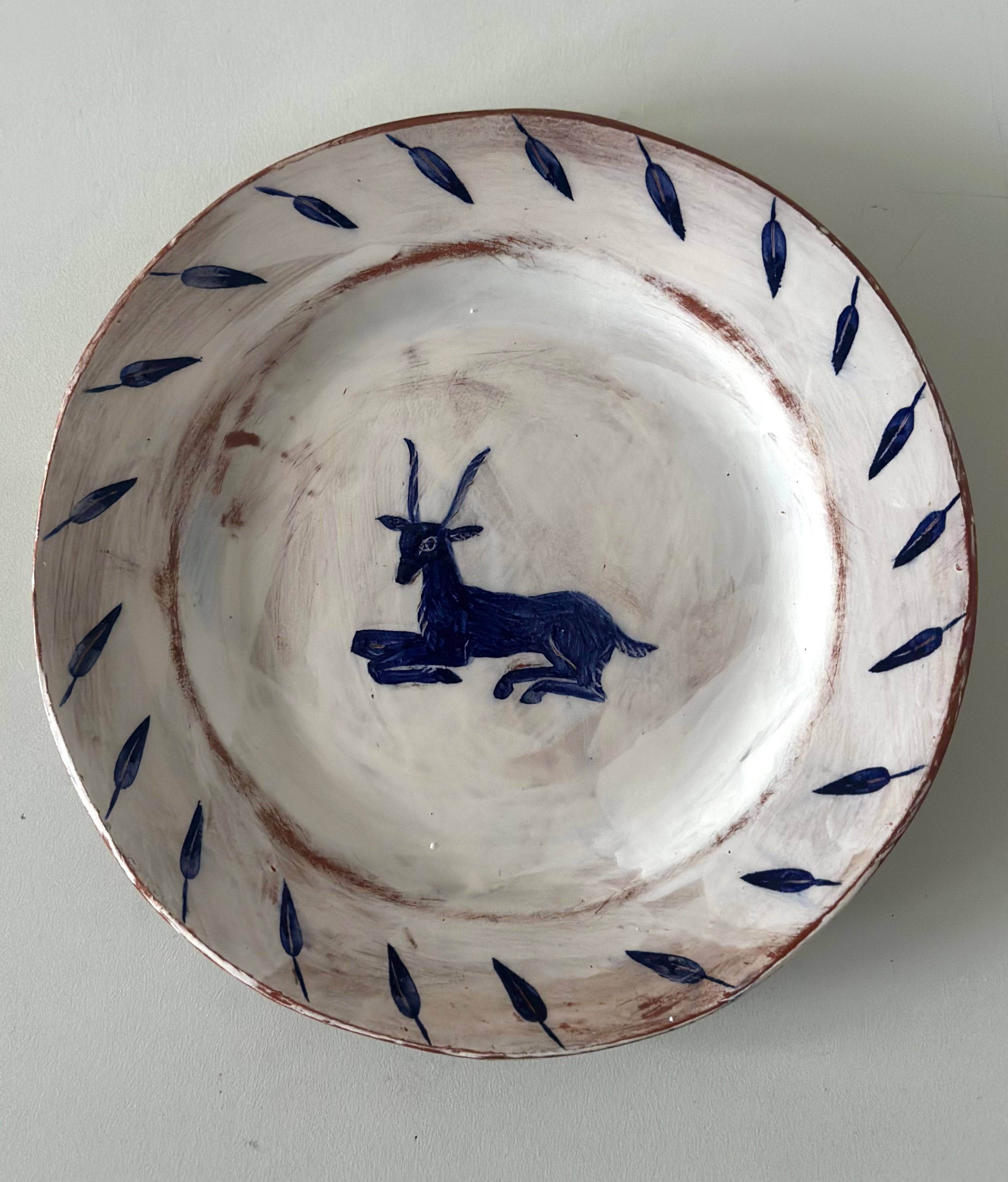 Ceramic plate with blue goat design on a white background