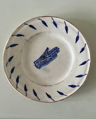 White ceramic dish with blue decorative elements on a plain background