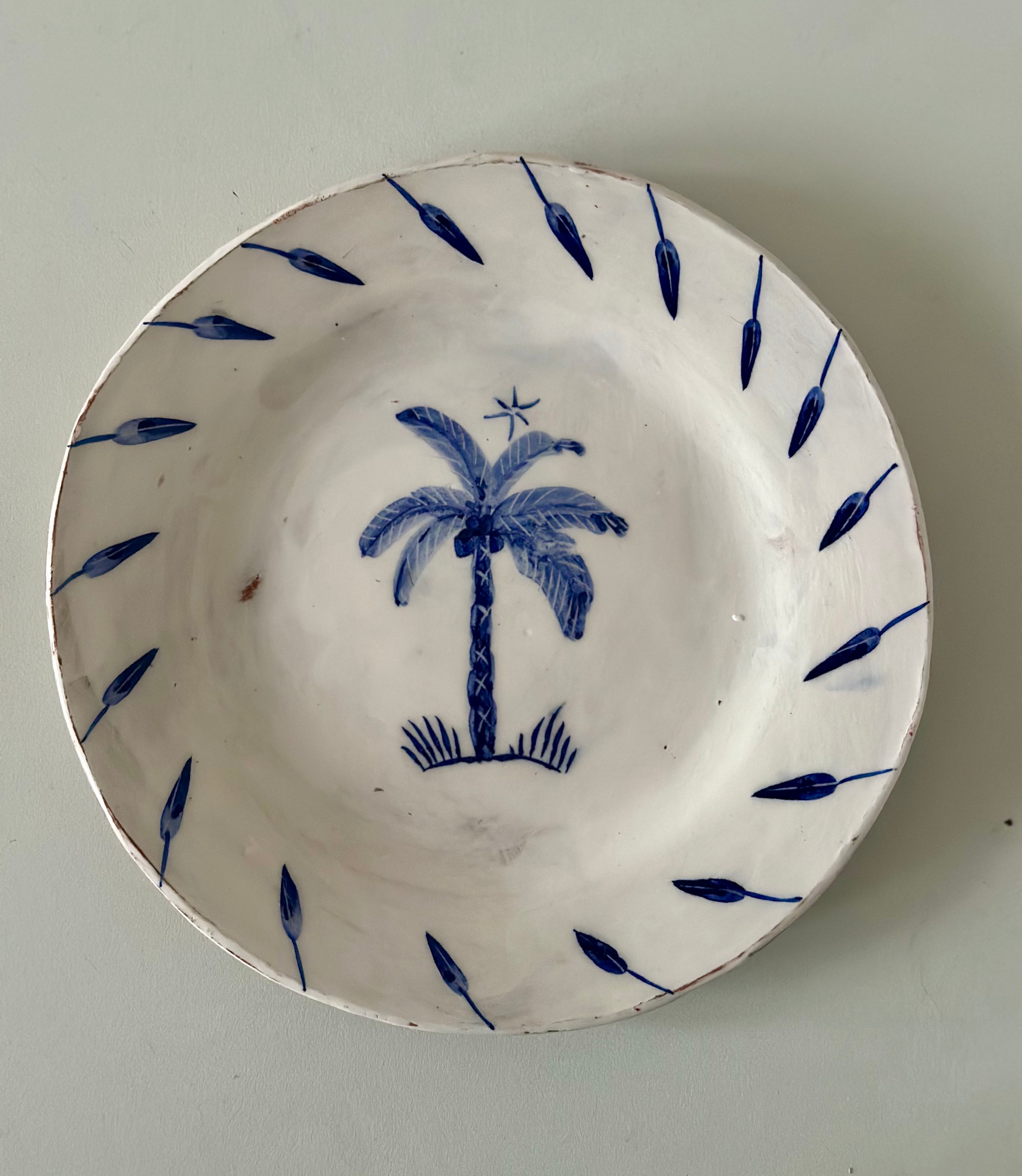 Ceramic plate with blue palm tree design on a plain background