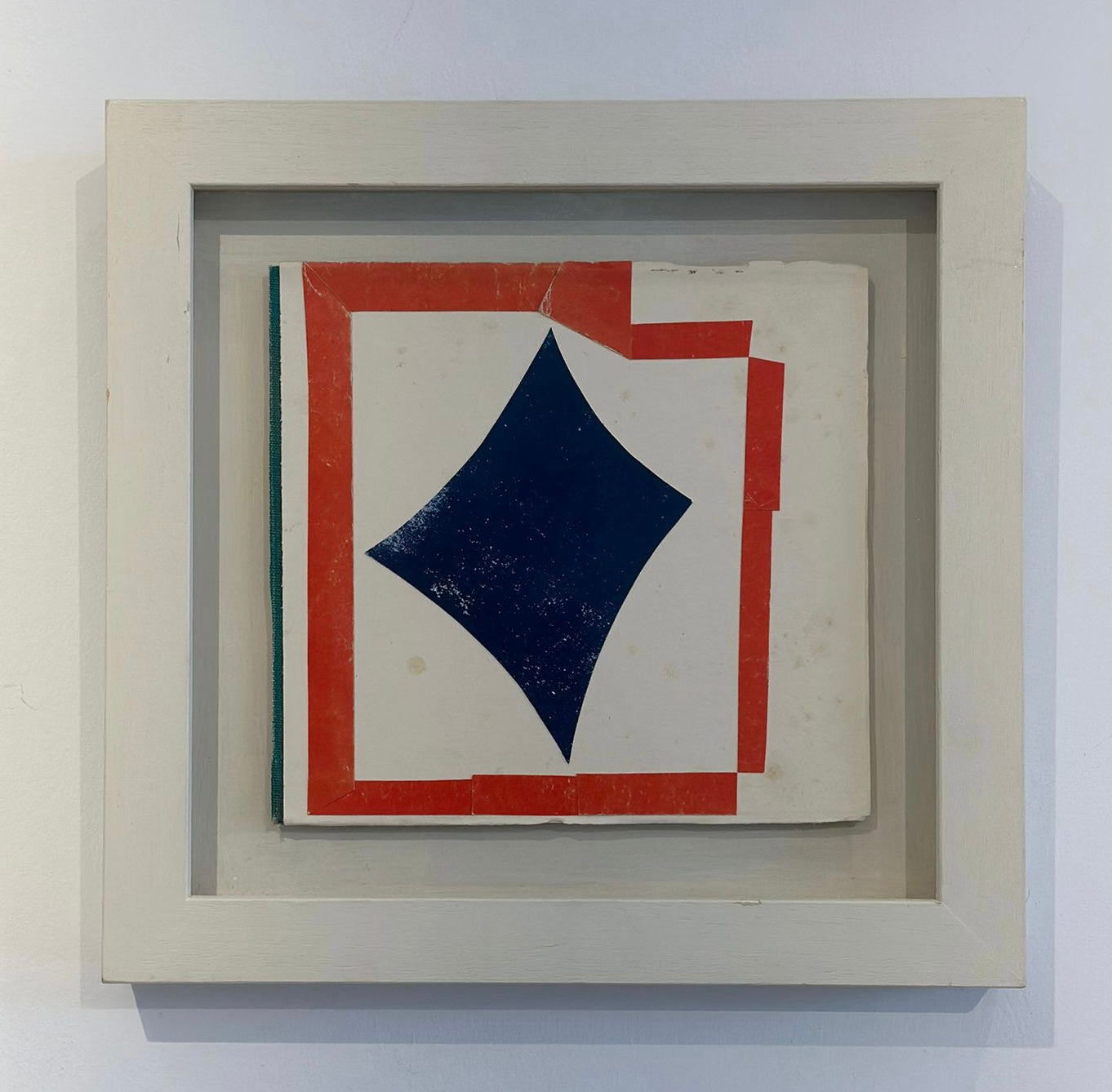 A found paper collage artwork titled 'Star' by Lauri Hopkins, featuring a geometric pattern with red, blue, and beige papers, framed in a light-colored enclosure.